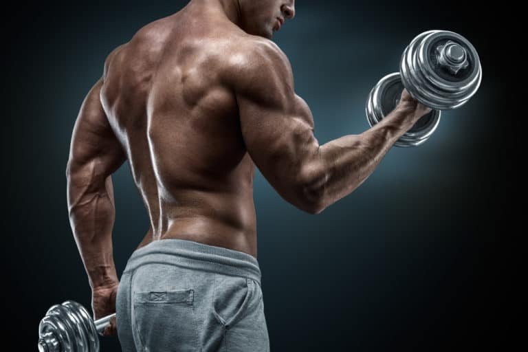 Power athletic man in training pumping up muscles with dumbbells