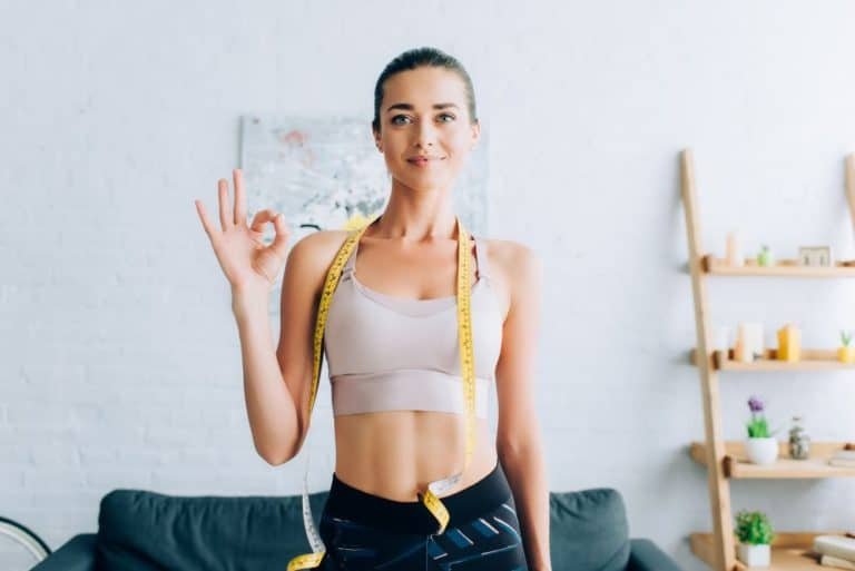 weight loss on a budget:Brunette sportswoman with measuring tape