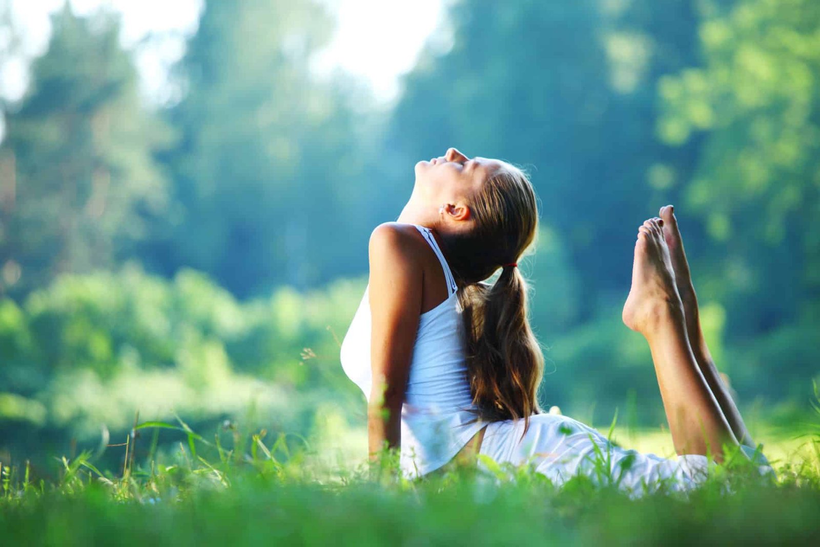 10 Yoga Practices for Healthy Aging 1 Yoga woman in white on green park grass in cobra asana pose