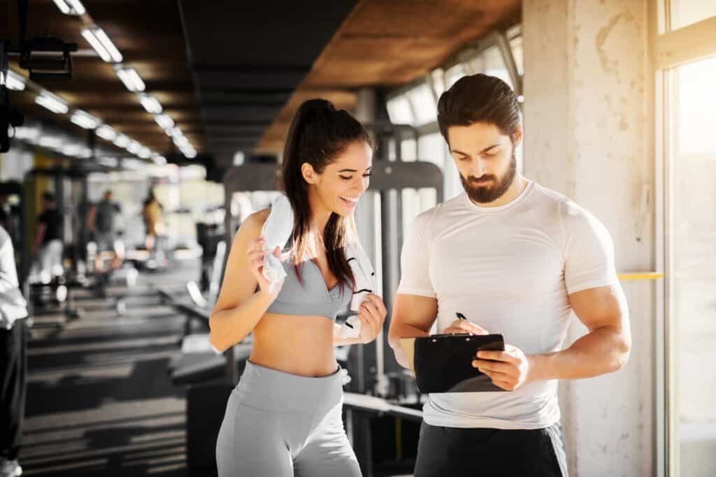 Why You Should Hire A Personal Trainer 4 Young slim fit woman standing with towel near handsome trainer