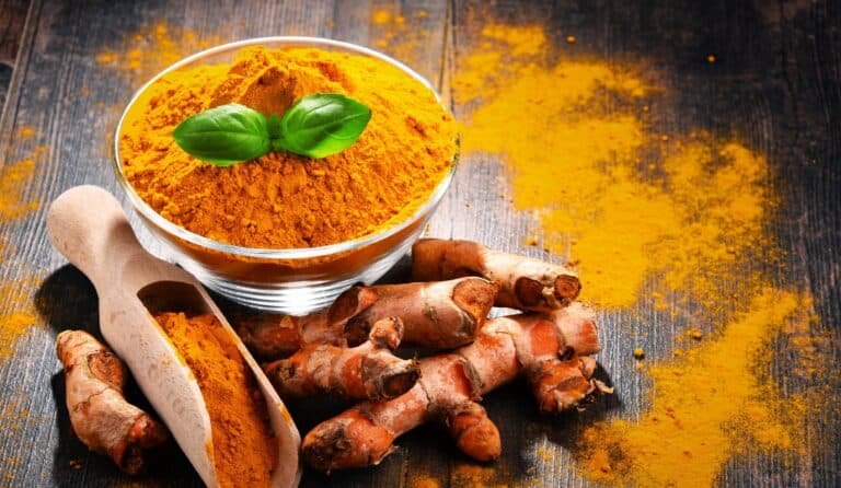 Composition with bowl of turmeric powder on wood