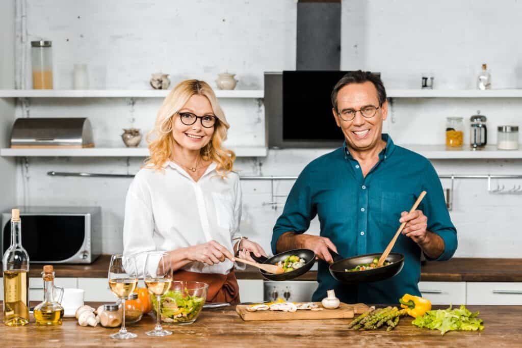How to Lose Weight After 50: Your Step-by-Step Guide 2 Mature wife and husband cooking and holding frying pans in kitchen