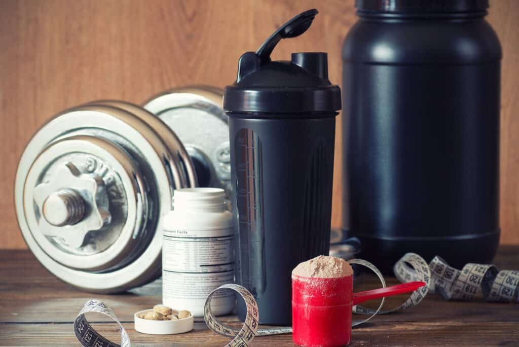 When to Take Workout Supplements: Optimal Timing for Maximum Benefits 2 Whey protein powder in scoop with vitamins on plate