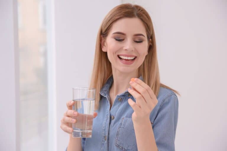 Young woman taking vitamin indoors