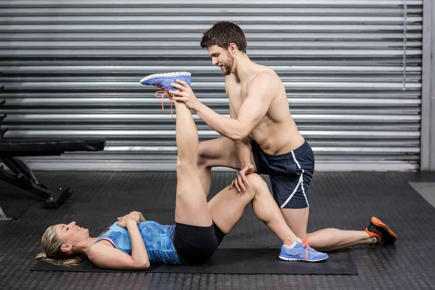 Benefits of Assisted Stretching: Enhancing Flexibility and Wellbeing 1 Benefits Of Assisted Stretching:Male trainer assisting woman stretching