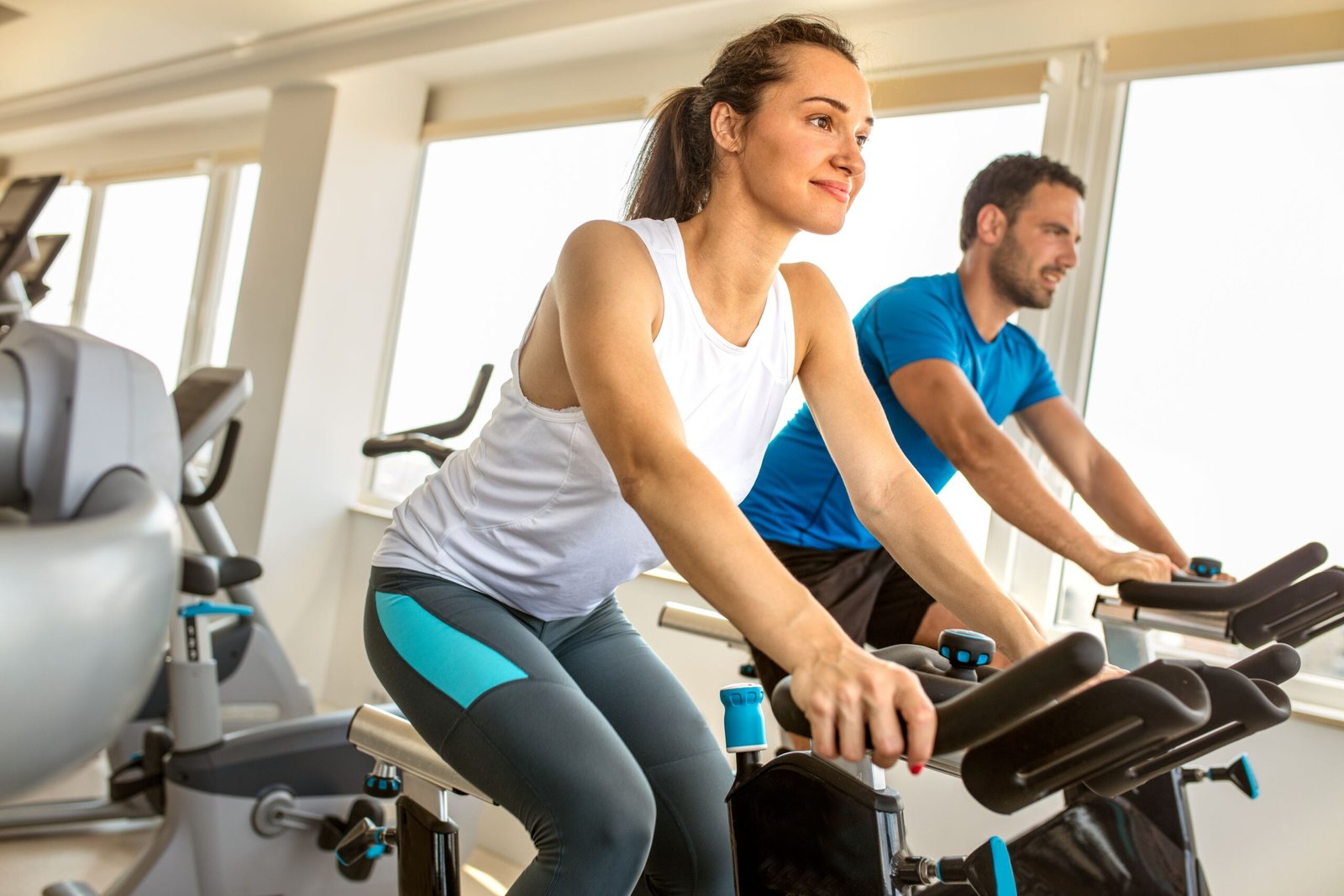 Young man and woman biking in the gym, exercise cardio