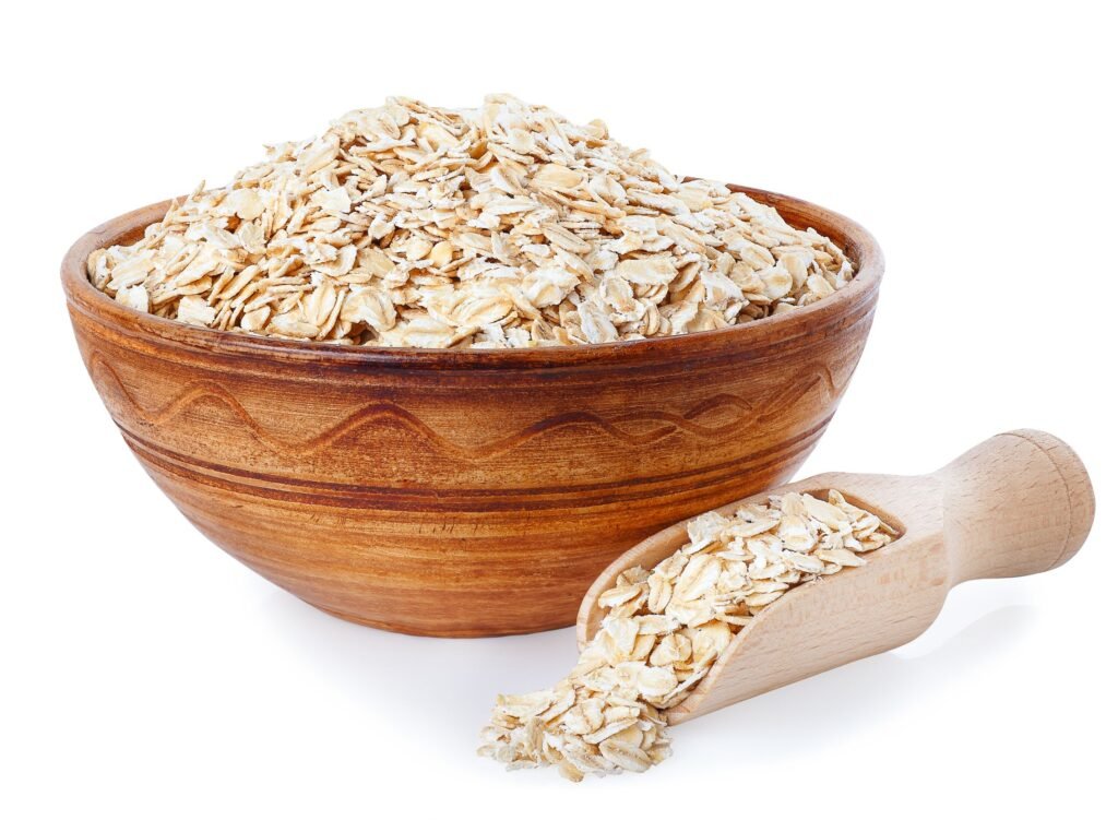 Oat flakes in bowl and wooden spoon on white background