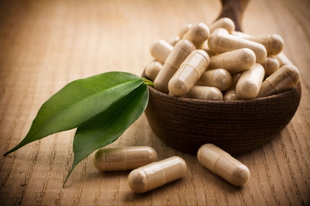 Alternative medicine tablets on a wooden spoon, green leaf