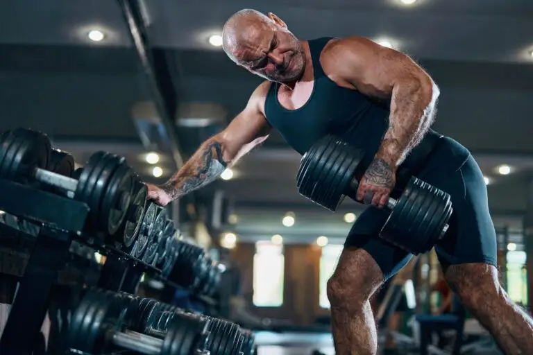 Aged man bodybuilder doing exercises with dumbbells